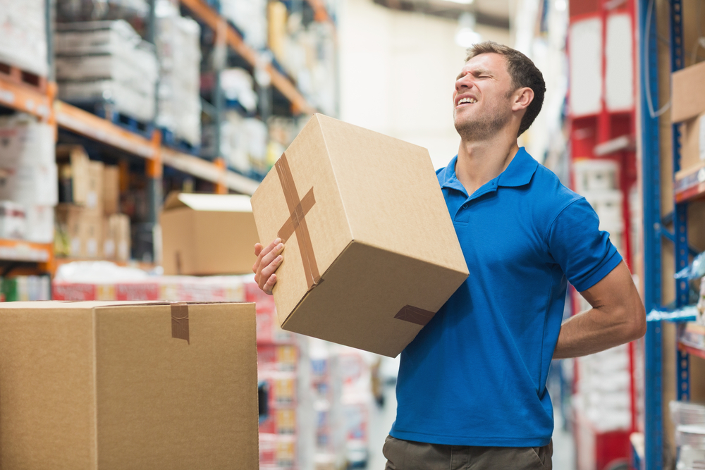 Side View Of Worker With Backache While Lifting Box